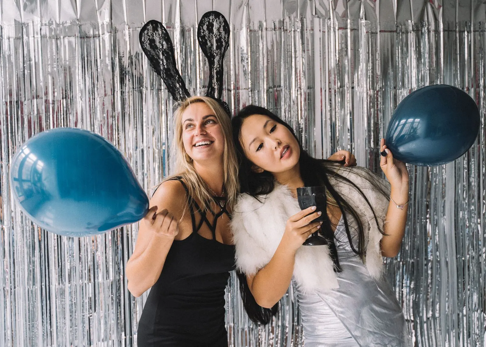 Friends posing in front of a tinsel backdrop at a photo booth rental in Chicago, IL