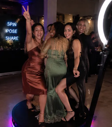 Friends in party dresses on a 360 photo booth platform