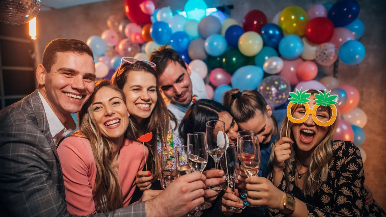 Guests toasting at a photo booth balloon wall
