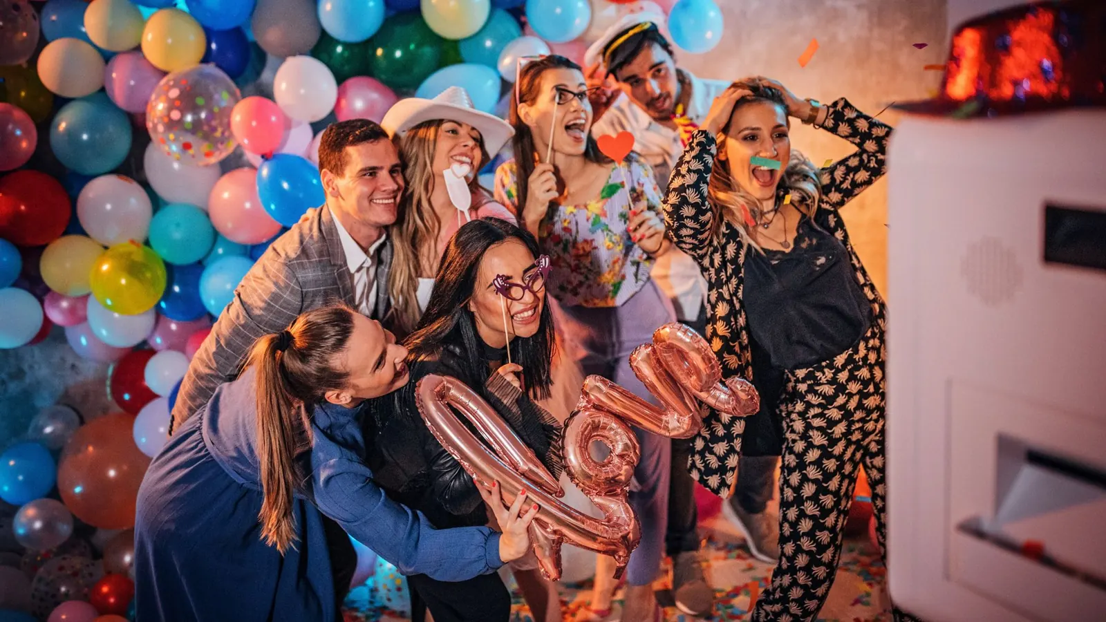 Group posing with props at a photo booth balloon backdrop
