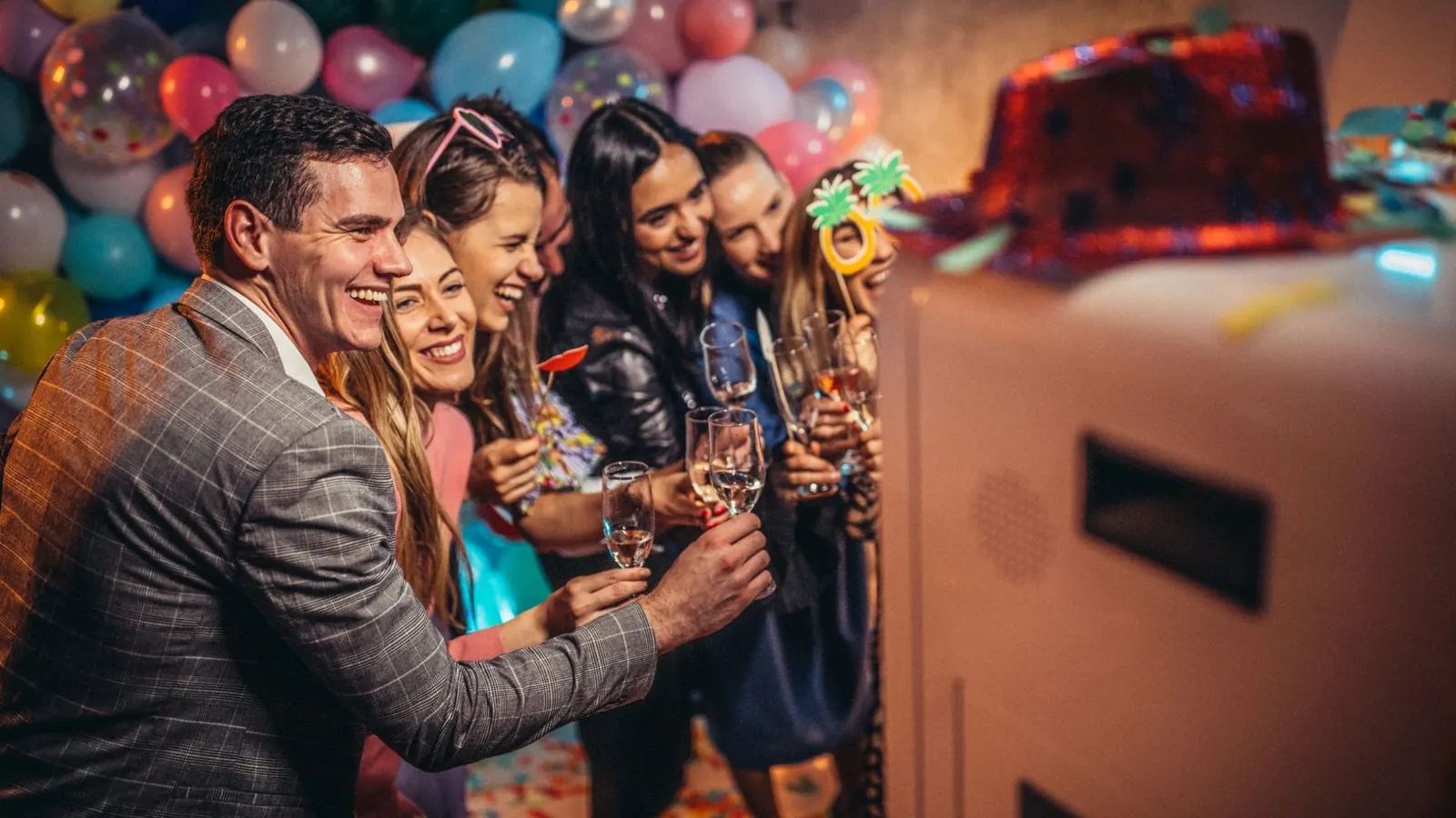 Guests posing next to a photo booth kiosk at a party