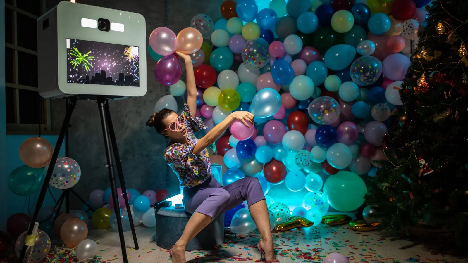 Guest posing at a photo booth kiosk in front of a balloon wall