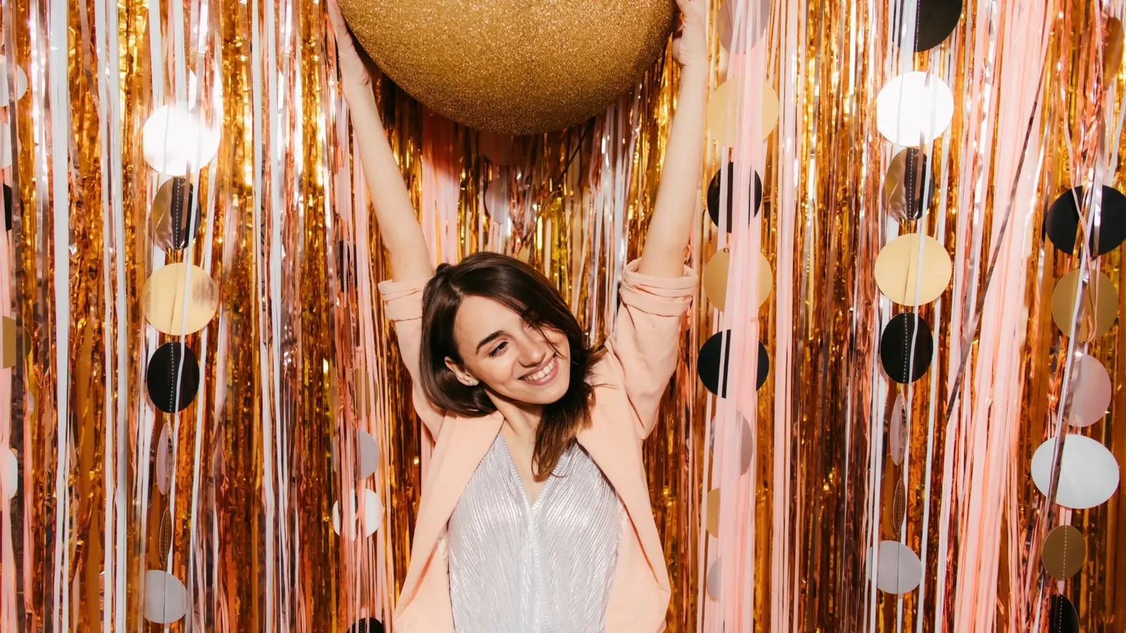 Woman posing at a gold tinsel photo booth backdrop